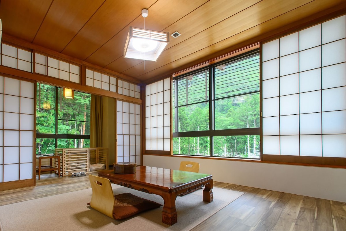 A traditional Japanese-style room with tatami flooring, a low wooden table, and sliding shoji doors.