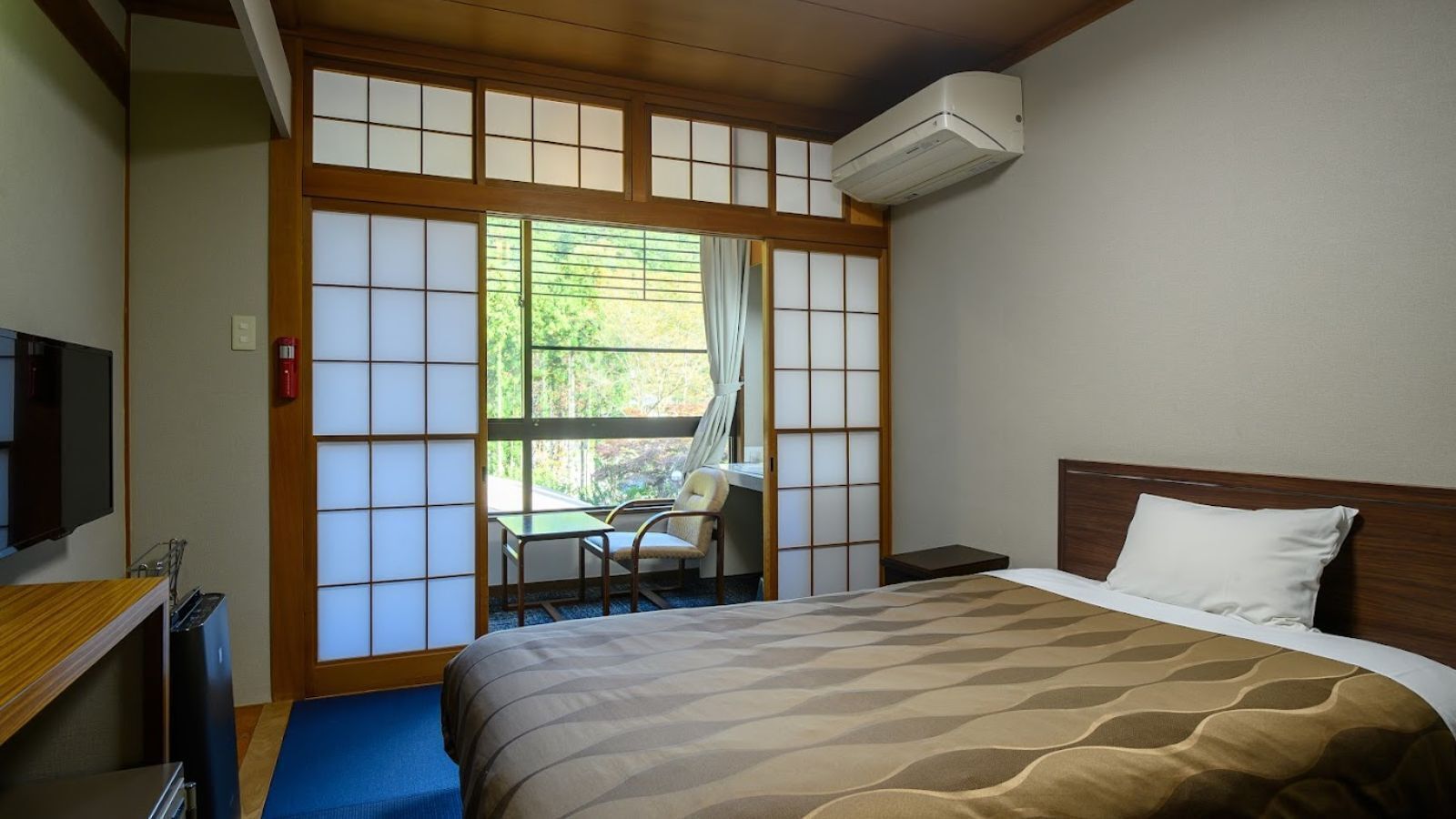 Una habitación de hotel con cama, escritorio, silla y televisor.
