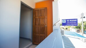 A hallway with a wooden door, a blue railing, and a sign indicating "S3 ROOM" with a contact number. - S3 Room (Sattahip)