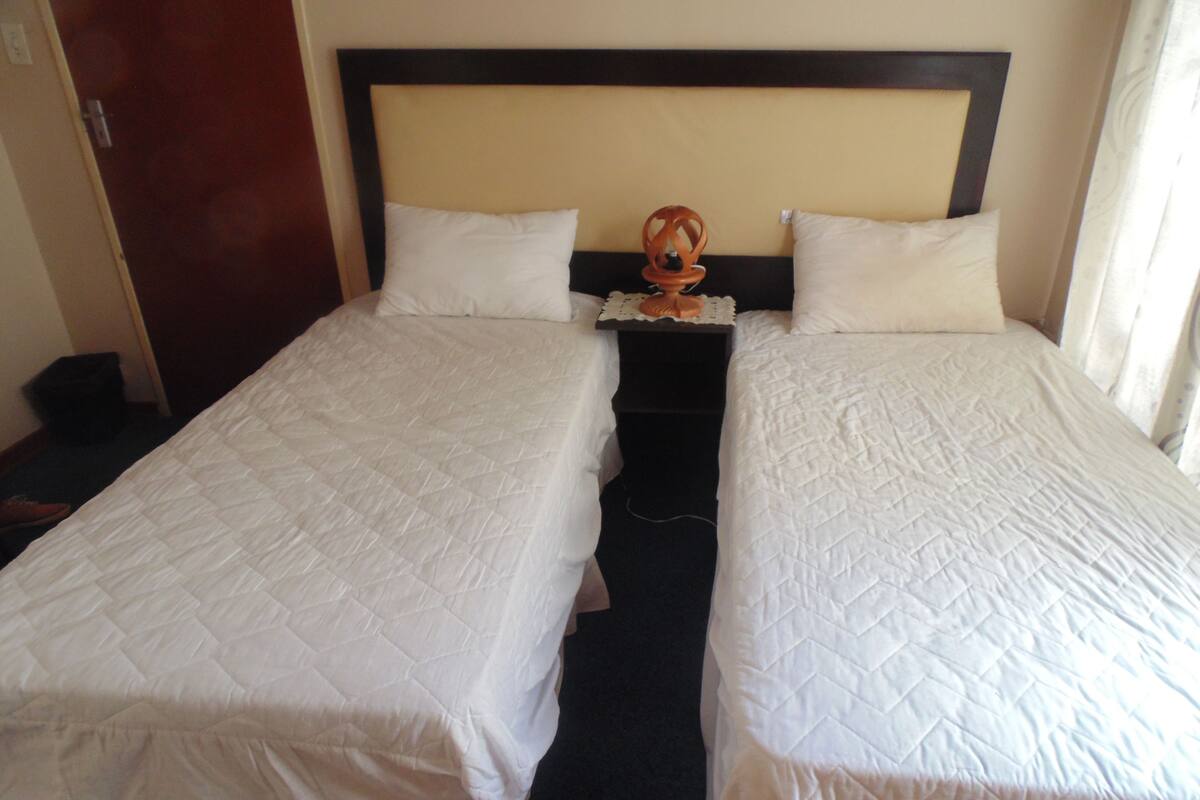 Una cama doble con cabecera de madera, dos almohadas blancas y un detalle decorativo en la mesita de noche.