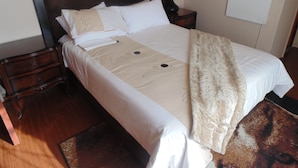 A neatly made bed with a headboard, a bedside lamp, and a whiteboard on the wall. - TDJ's B&B (Soweto)
