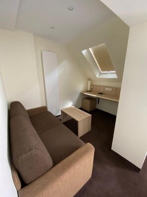 A compact living space with a sofa, a small table, a kitchenette, and a skylight. - Hotel Alt Westerholt (Herten)