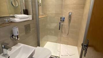 Ein modernes Badezimmer mit einer gläsernen Duschkabine, einem weißen Waschbecken und einer Toilette.