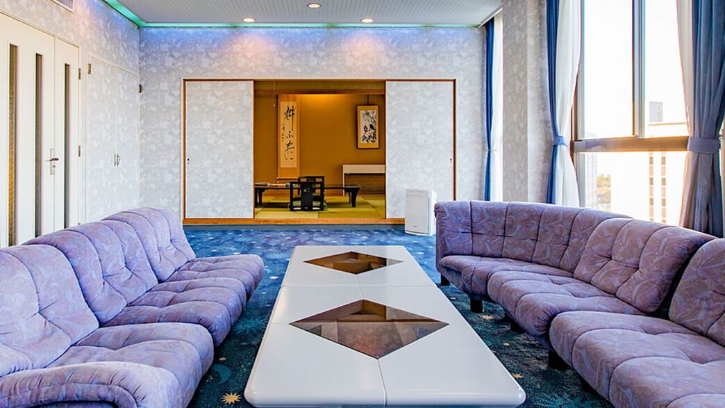 Una habitación con dos sofás, una mesa de centro y vistas a una habitación tradicional japonesa al fondo.