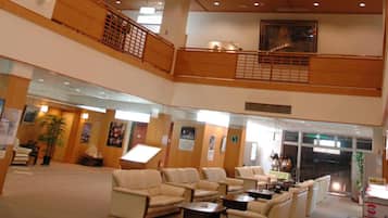 A spacious lobby with multiple seating areas, a staircase, and a reception desk.
