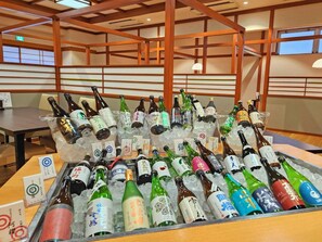 Diversa bottiglie in un contenitore, probabilmente per una degustazione, in una stanza con travi in legno e un tavolo.