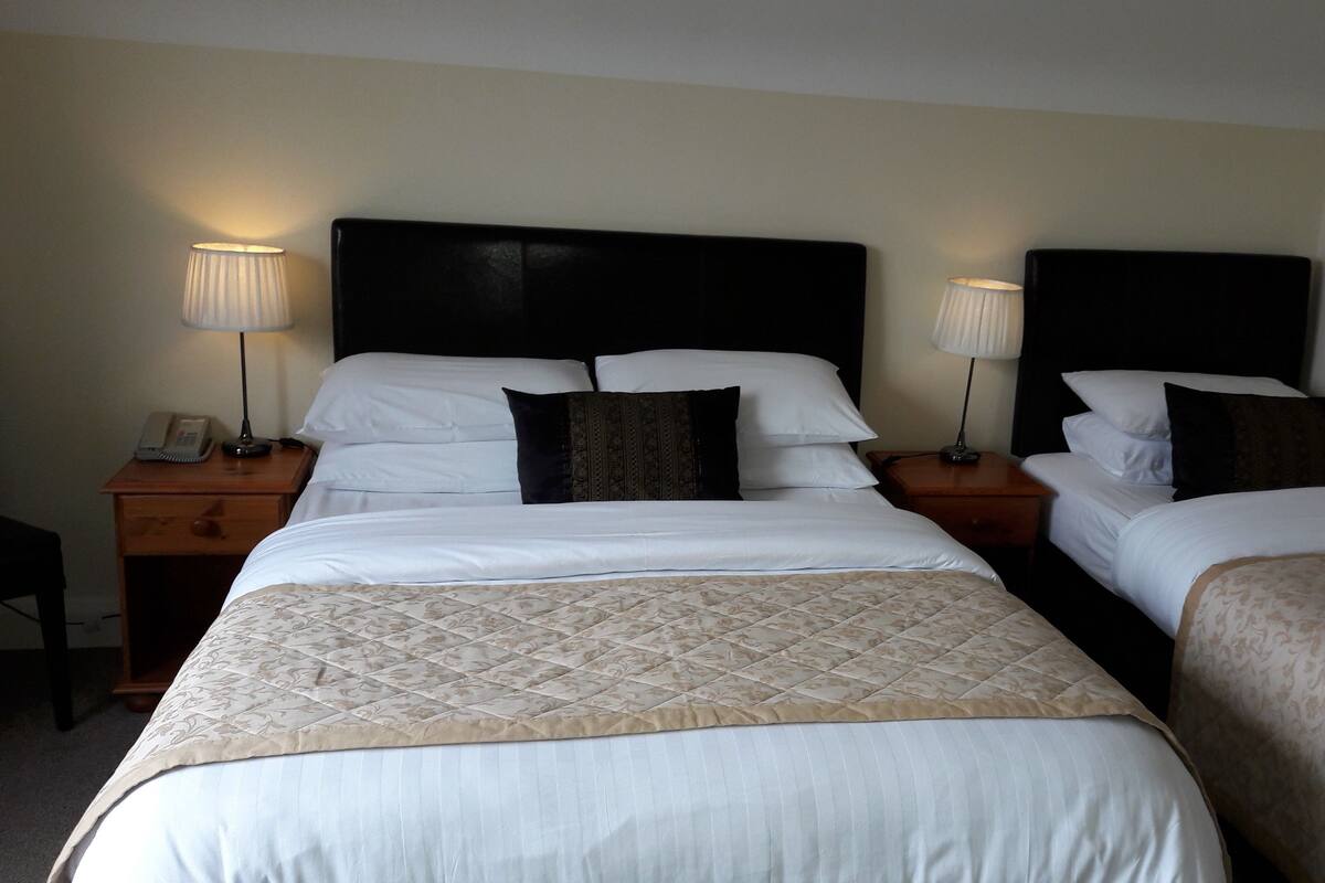 A hotel room with two beds, each with a headboard, bedside tables, lamps, and a telephone.