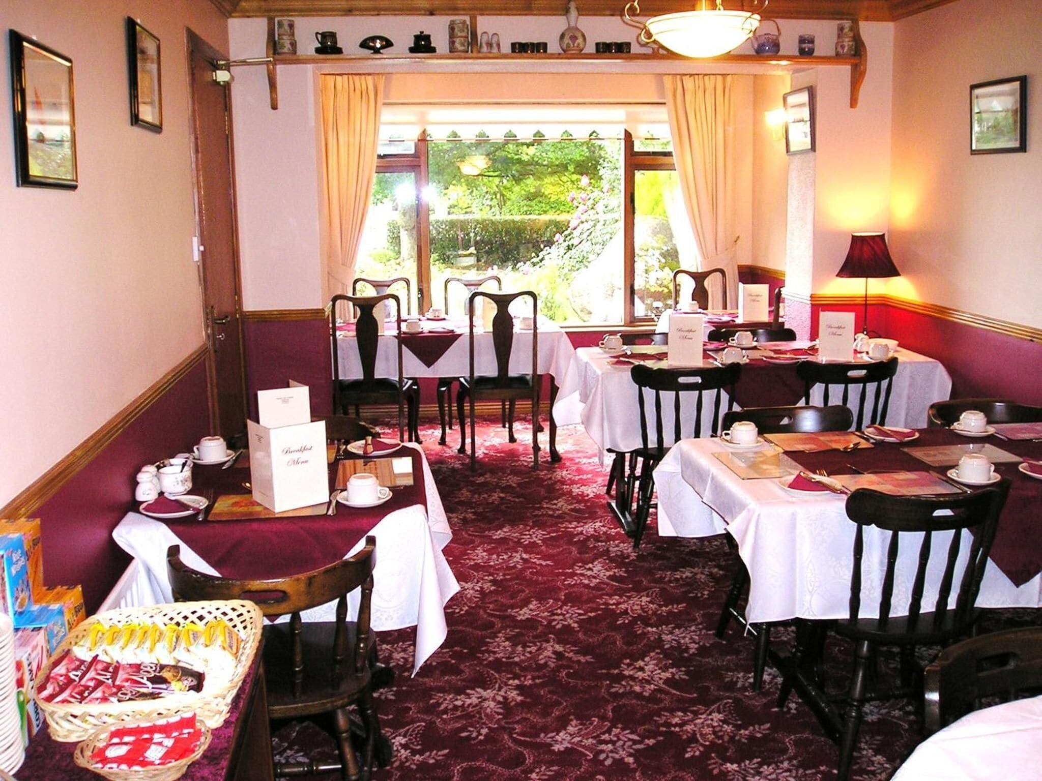 A dining area with tables set for service, chairs, and a carpeted floor.