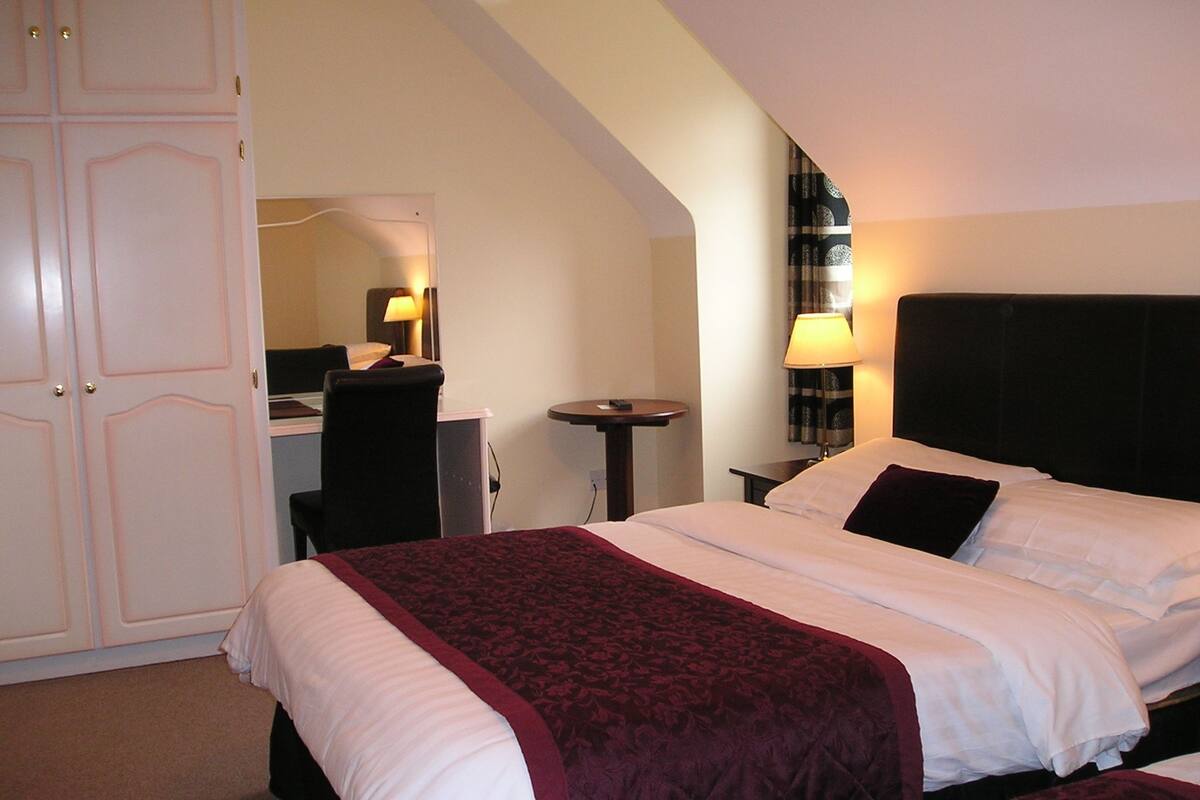 A hotel room with a bed, a desk, and a chair.