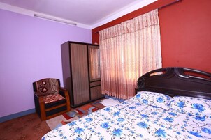 A bedroom with a bed, a wardrobe, a chair, and a curtain.