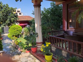 Un patio con plantas en macetas, una baranda de madera y un edificio con techo rojo.