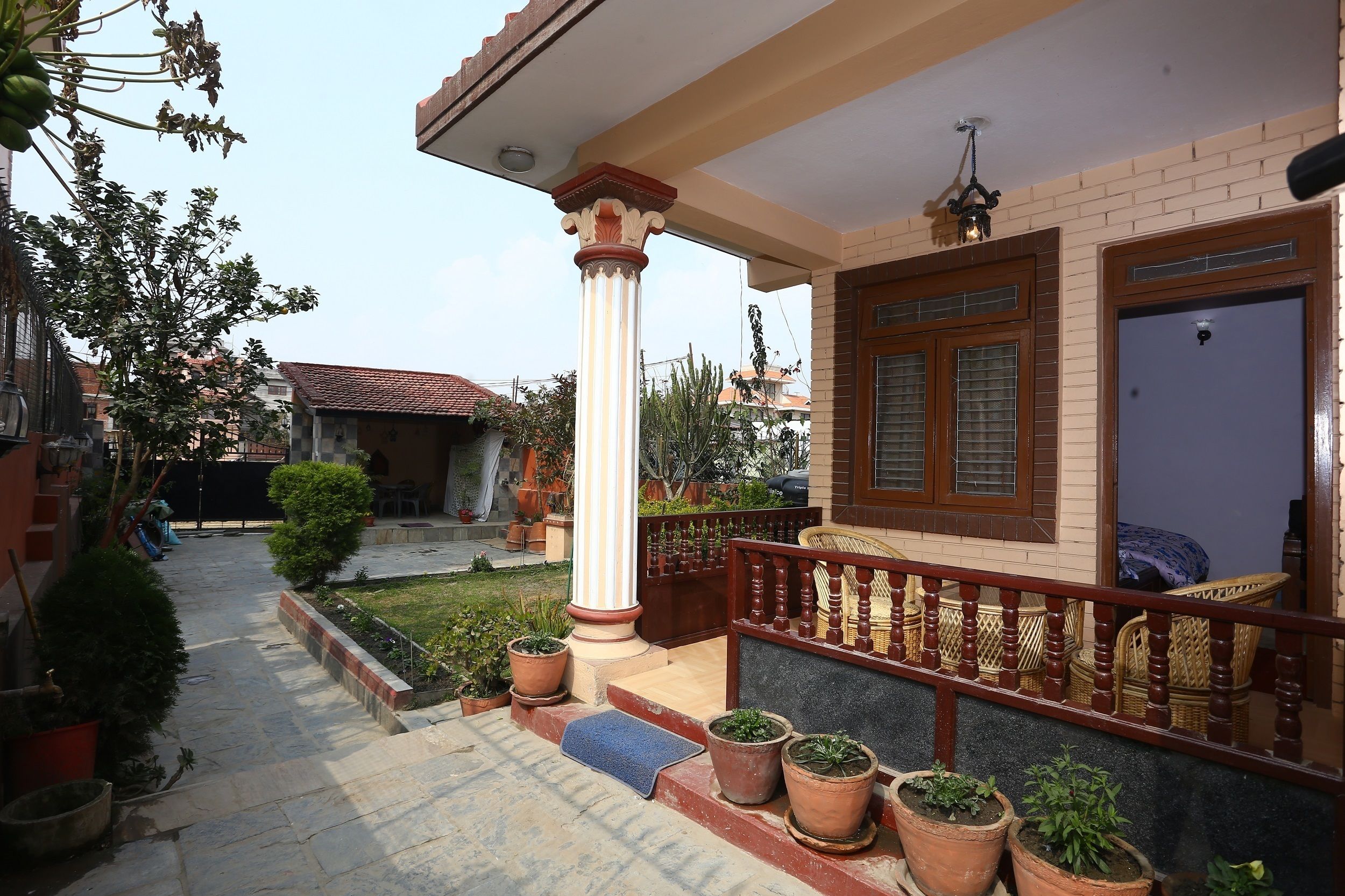 A residential building with a porch, potted plants, and a staircase leading to the entrance.