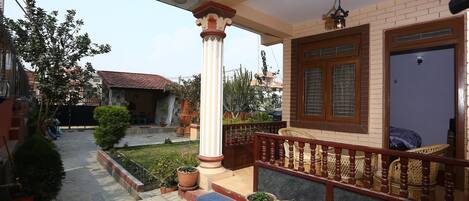 A residential building with a porch, potted plants, and a staircase leading to the entrance.