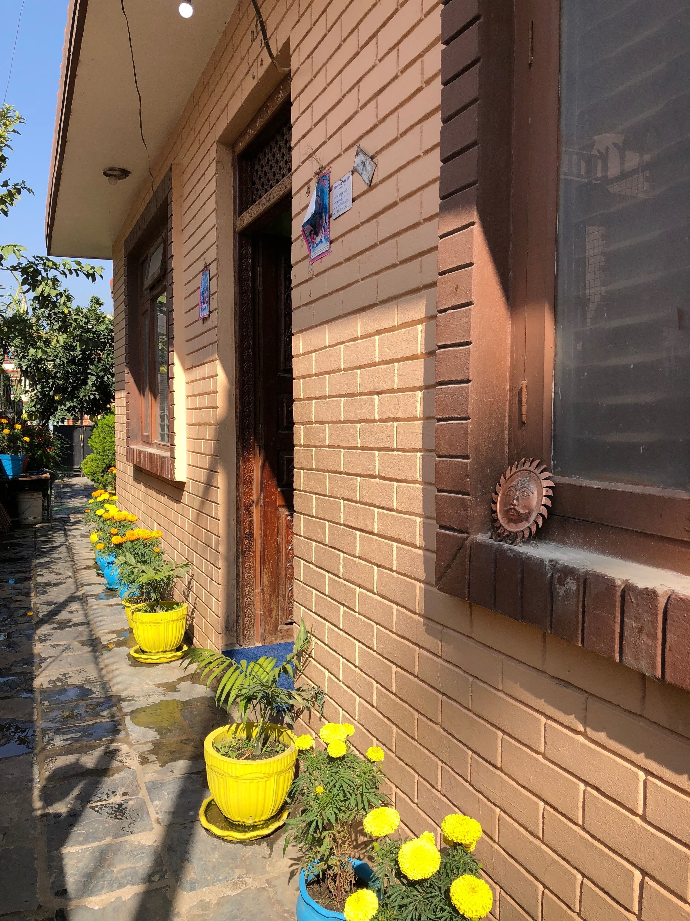 A building with a brick exterior, a window with a decorative plate, and a door with a small sign.