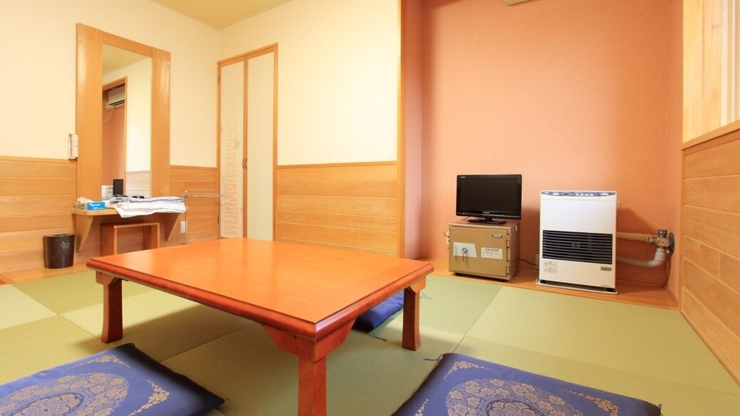 A room with a wooden table, a television, and a heater.