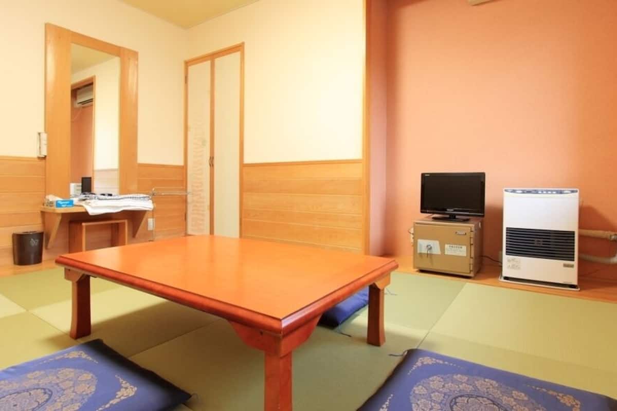 Una habitación con una mesa de madera, televisor y calefactor.