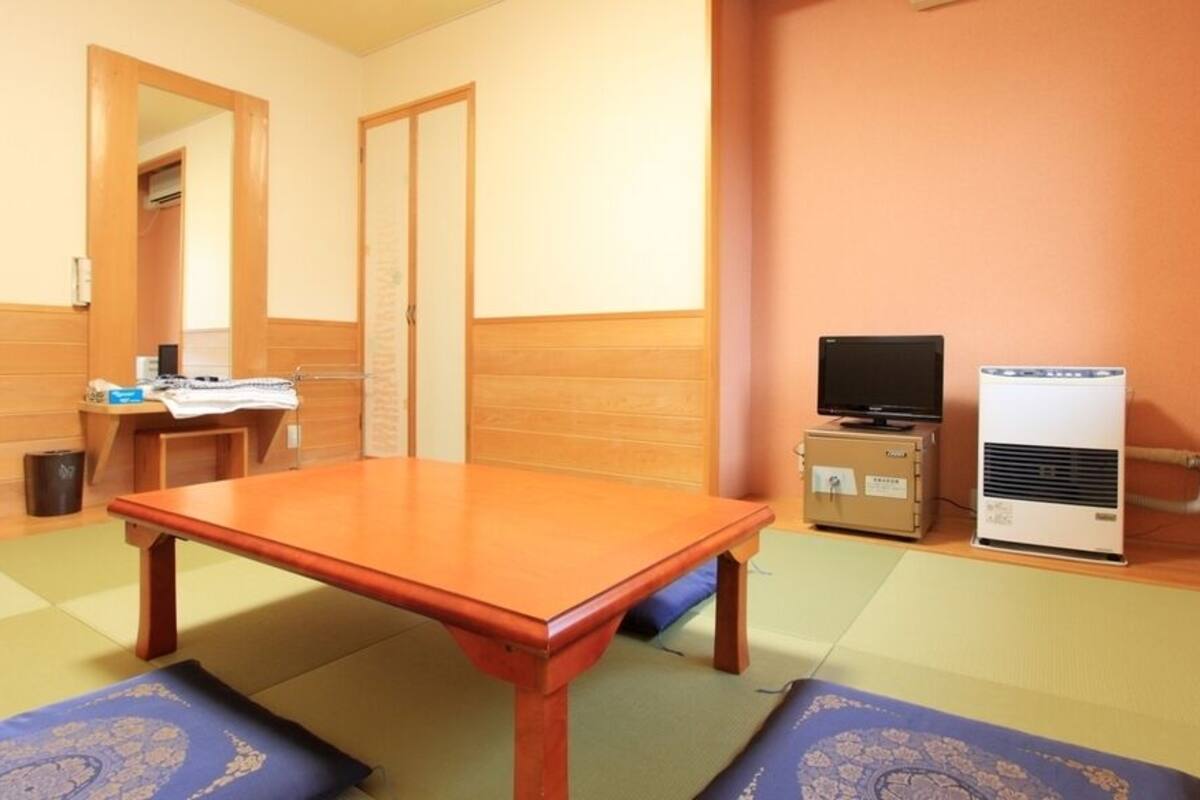A room with a wooden table, a television, and a heater.