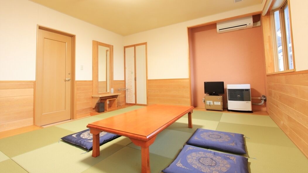 A room with a wooden floor, a table, a television, and an air conditioner.