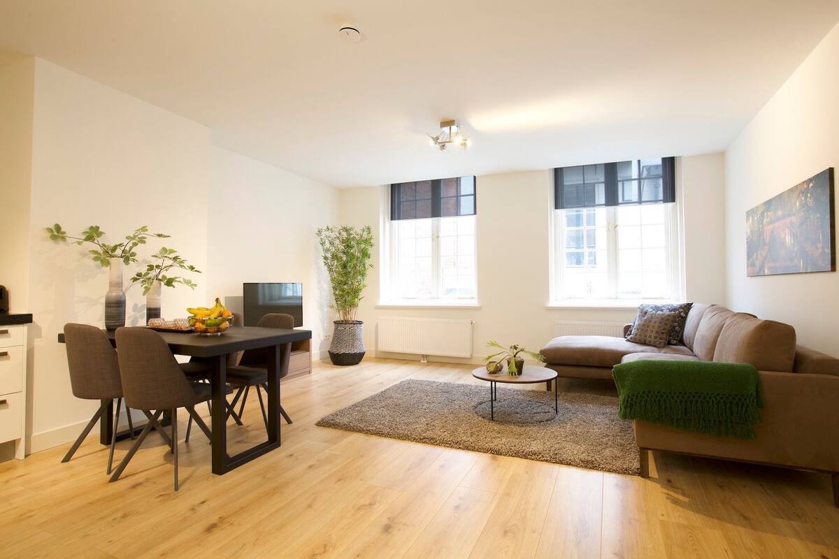 A modern living room with a dining area, a sofa, a coffee table, and a TV.