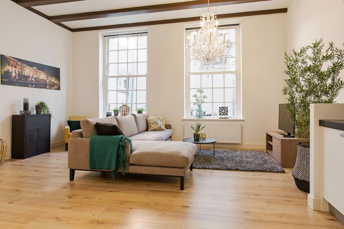 A living room with a sofa, a small table, a plant, and a painting on the wall.