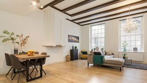 A spacious living area with a wooden dining table, a sofa, and a chandelier.