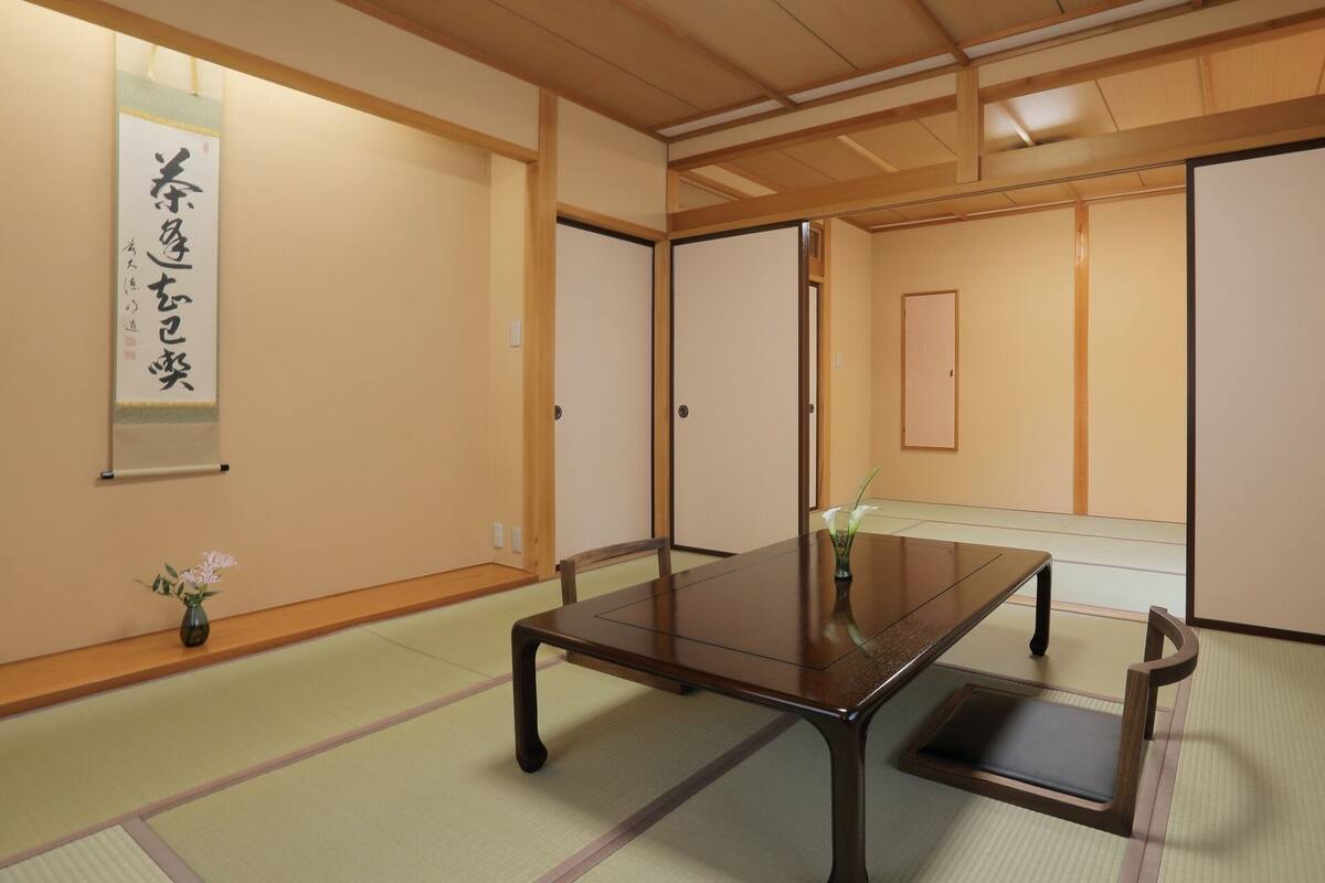 Een traditionele Japanse kamer met tatami vloeren, een lage tafel, schuifdeuren en een kalligrafie rol.