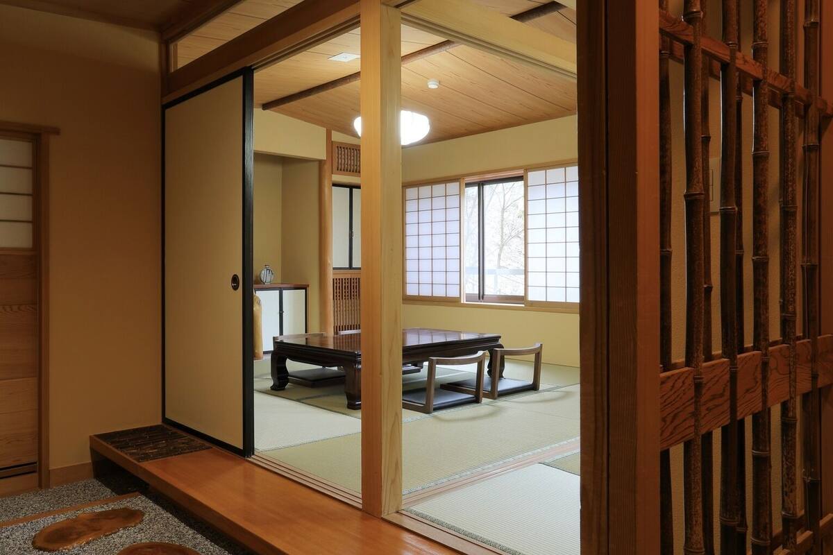 Een traditionele Japanse kamer met tatami vloerbedekking, een schuifdeur, een houten tafel en uitzicht door de deur.