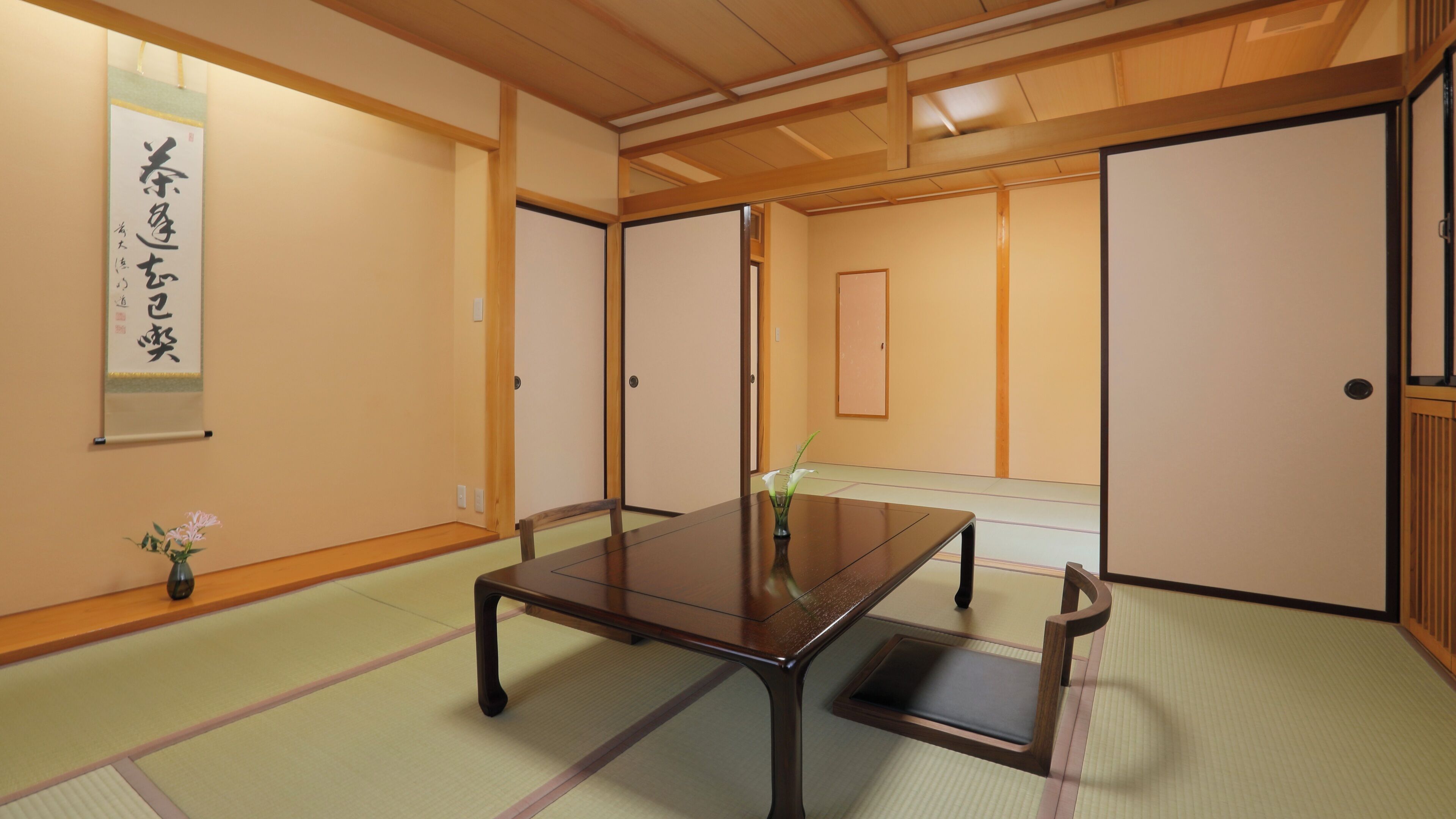 A traditional Japanese room with tatami flooring, a low wooden table, and sliding doors.