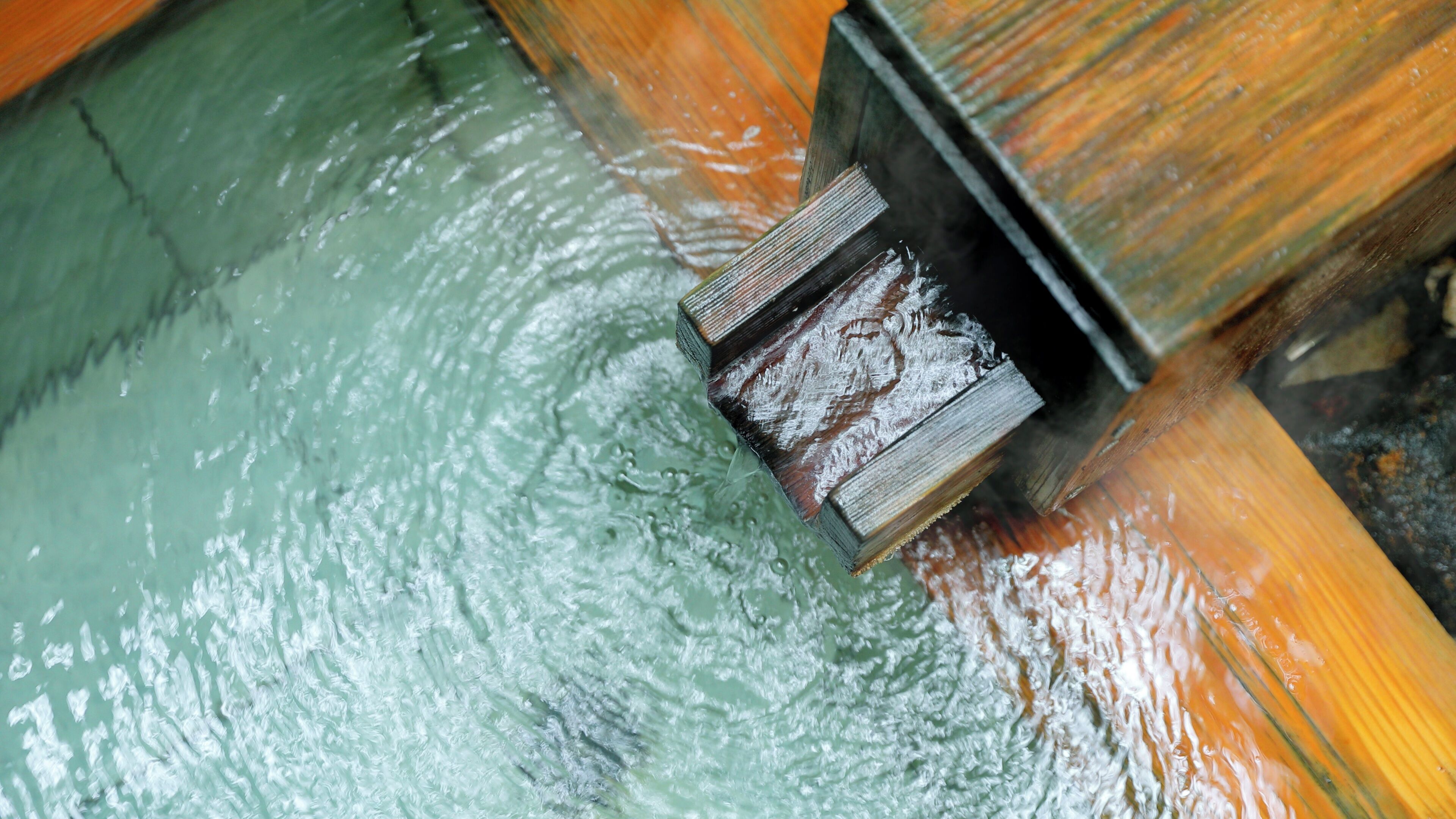 A close-up of a wooden structure with a water feature, possibly part of a building's architecture.