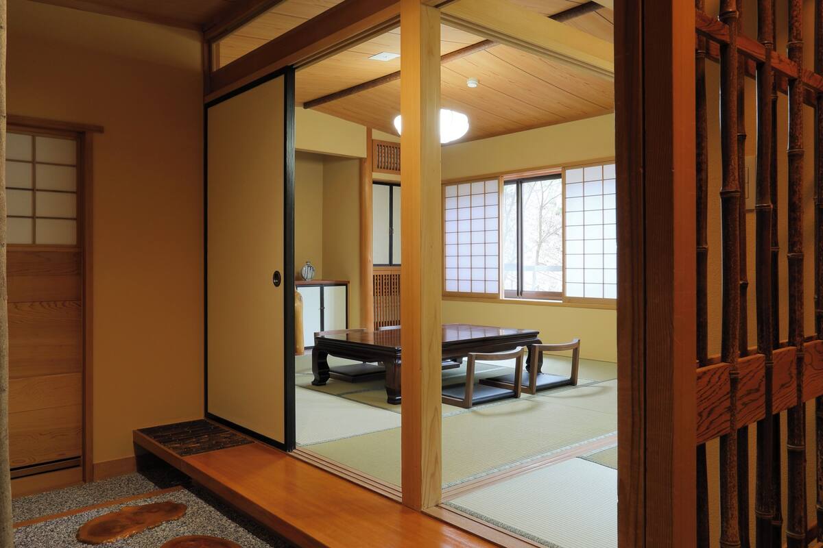 Een traditionele Japanse kamer met tatami vloeren, een schuifdeur en uitzicht op een eetgedeelte.