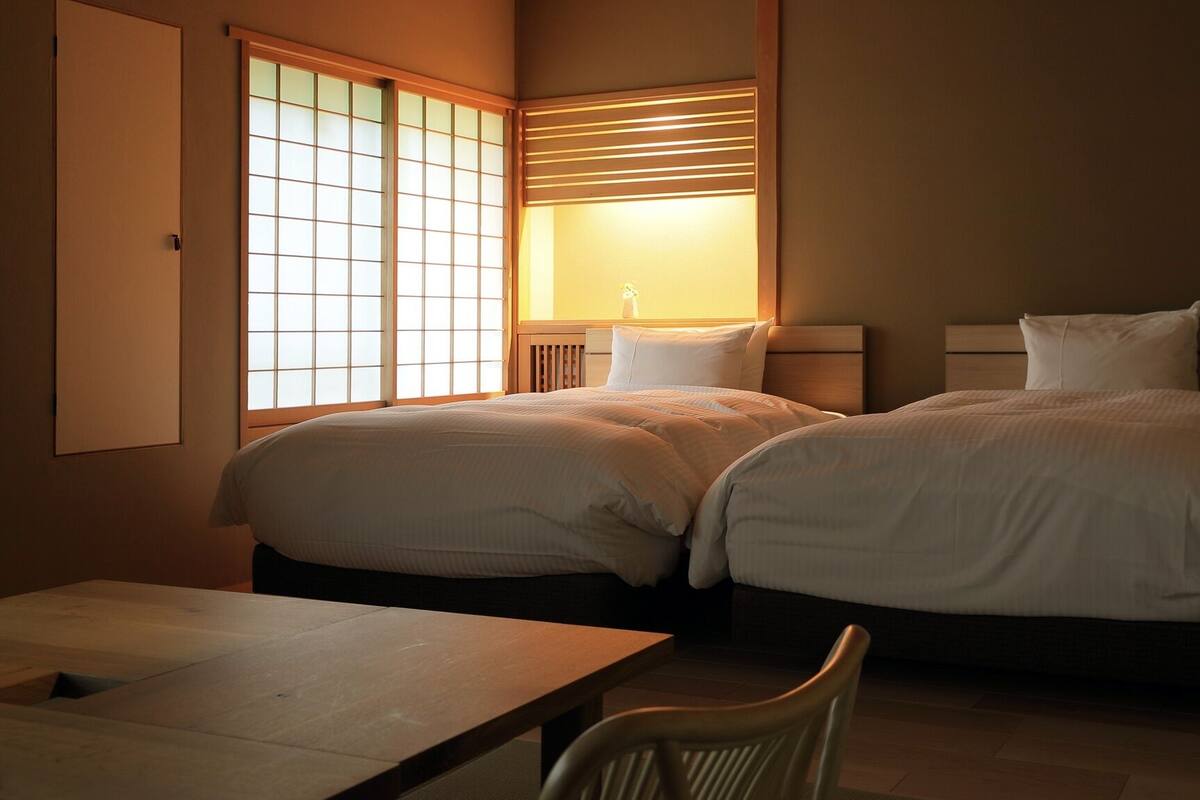 Een kamer met twee bedden, een tafel en een stoel.