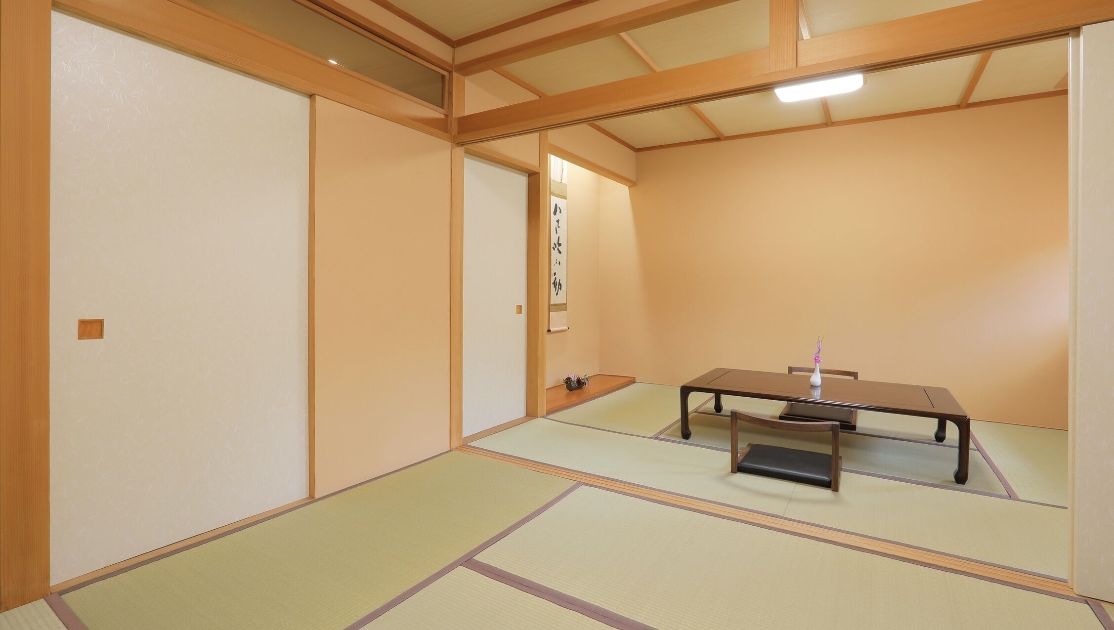 A traditional Japanese room with tatami flooring, a low table, and sliding doors.
