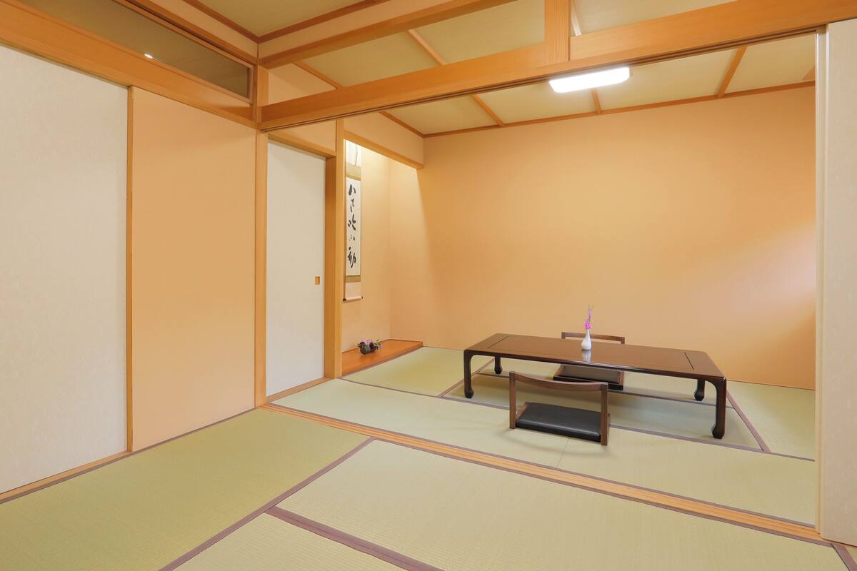 Een traditionele Japanse kamer met tatami vloerbedekking, een lage tafel en schuifdeuren.