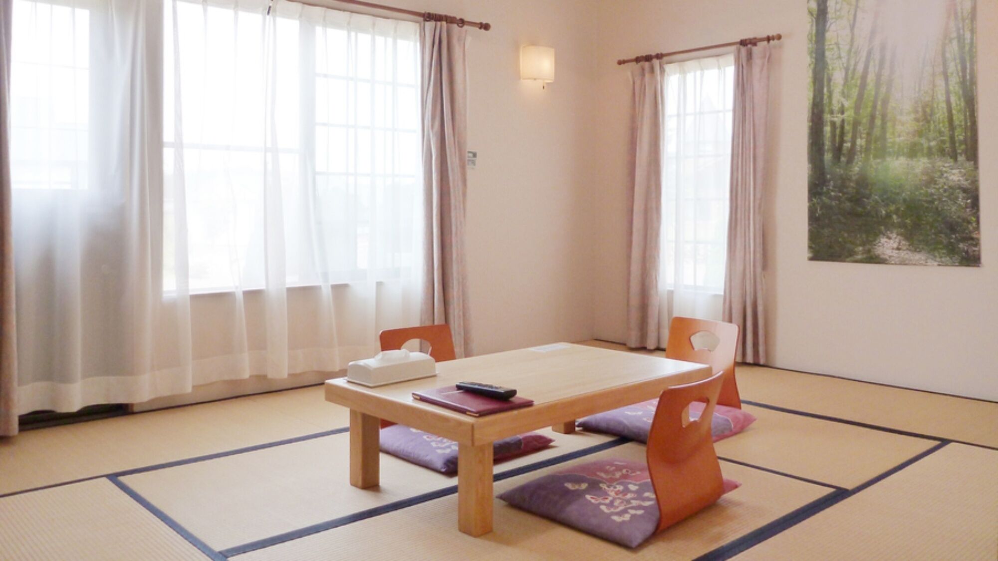 A traditional Japanese room with tatami flooring, a low wooden table, and two orange chairs.