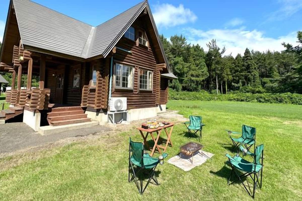 Une cabane en rondins avec un porche, un espace salon extérieur et un foyer.