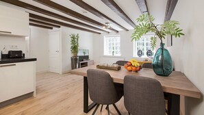 A modern kitchen with a wooden dining table, two grey chairs, and a fruit bowl. - Canal Garden Apartment 11 (Utrecht)