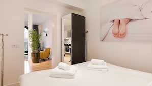 A hotel room with a bed, two towels, a potted plant, a chair, and a painting on the wall. - Canal Garden Apartment 11 (Utrecht)