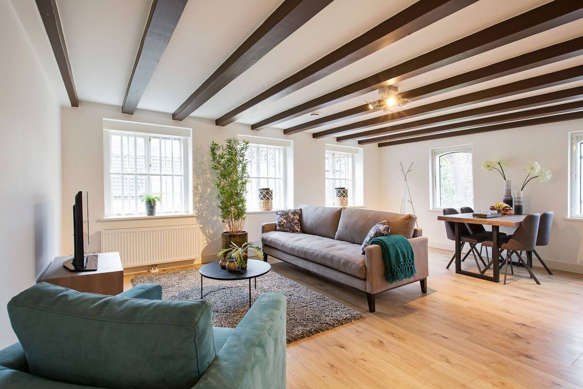 Uma sala de estar moderna com um sofá, uma mesa de centro e um espaço de jantar com cadeiras e uma mesa.