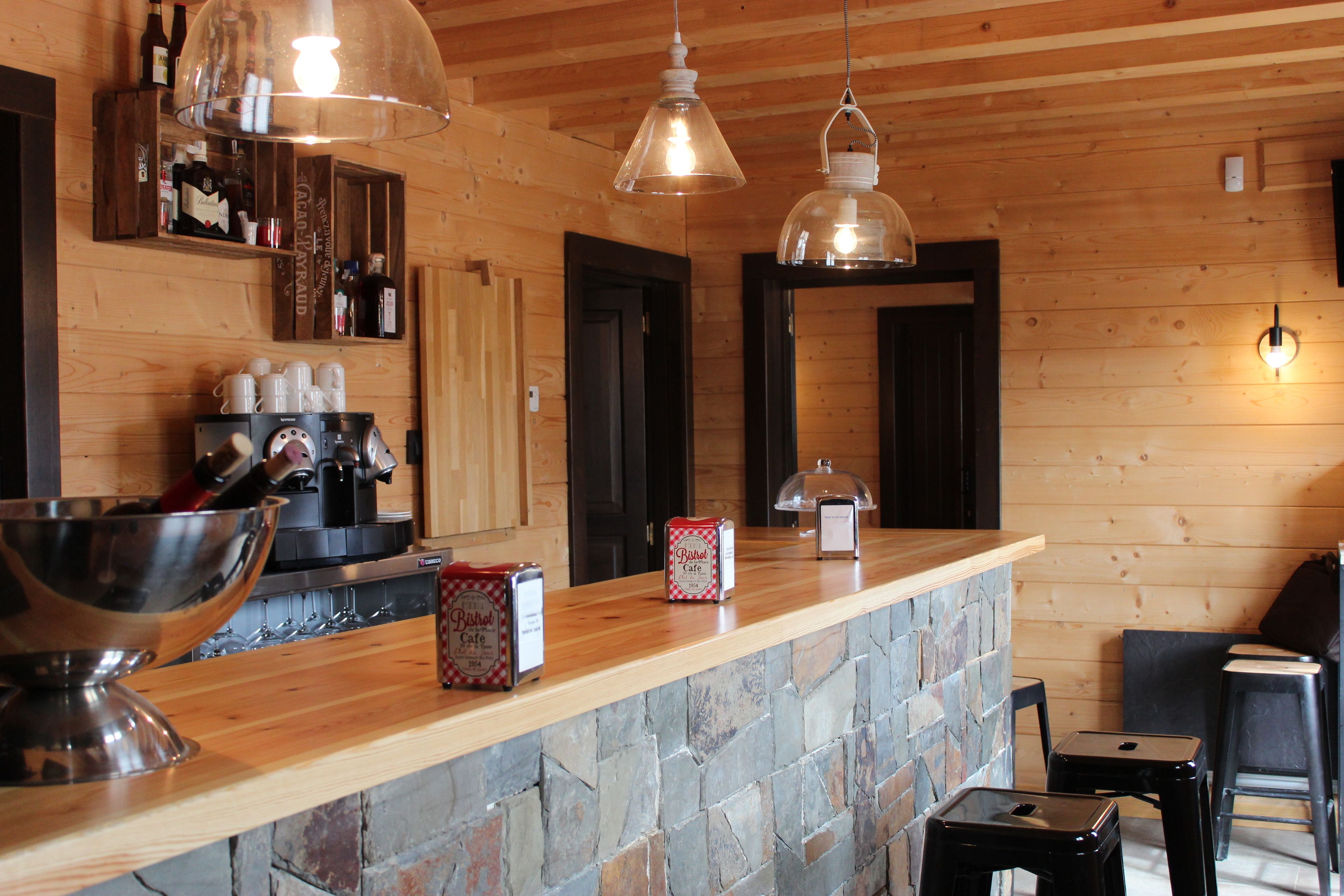 Een houten interieur met een stenen aanrecht, een koffieapparaat en een menukaartstandaard.
