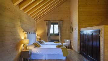 A cozy wooden cabin bedroom with two beds, a nightstand with a lamp, a chair, and a wardrobe.