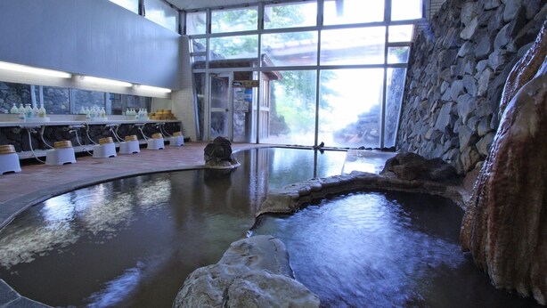 Een wellnessruimte met een jacuzzi, stenen muren en uitzicht op de omgeving.
