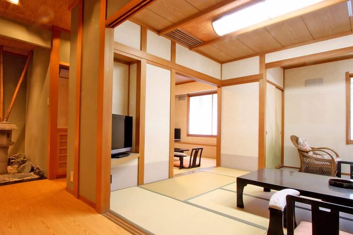 Una habitació japonesa tradicional amb tatami, televisió, taula i cadira.