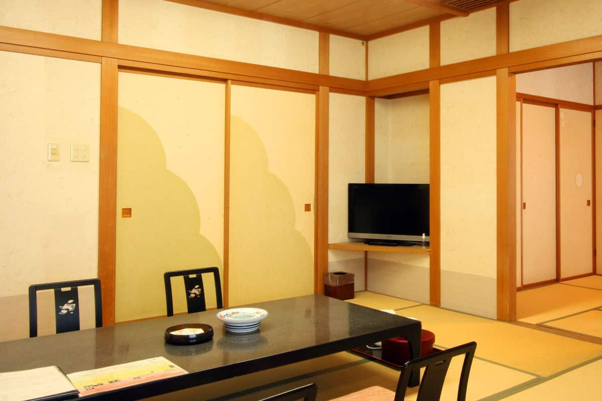 Una habitació tradicional japonesa amb sòls de tatami, una taula baixa amb televisió i portes corredisses.