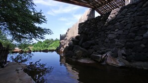Een stenen muur, een houten brug en een waterpartij.