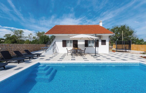 A modern house with a swimming pool, a covered patio with outdoor furniture, and a stone wall. - Pet friendly home in Unesic (Unesic)