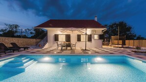 Uma casa moderna com piscina, móveis de exterior e um muro de pedra.