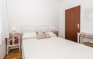 A bedroom with a bed, two bedside tables, a wooden door, and a small table with a mirror. - Pet friendly home in Unesic (Unesic)