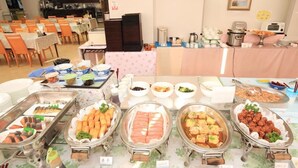 Un buffet proposant une variété de plats, notamment des sushis, des raviolis et un plat mijoté.