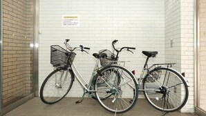 Trois vélos sont garés contre un mur de briques blanches, dans un espace carrelé.