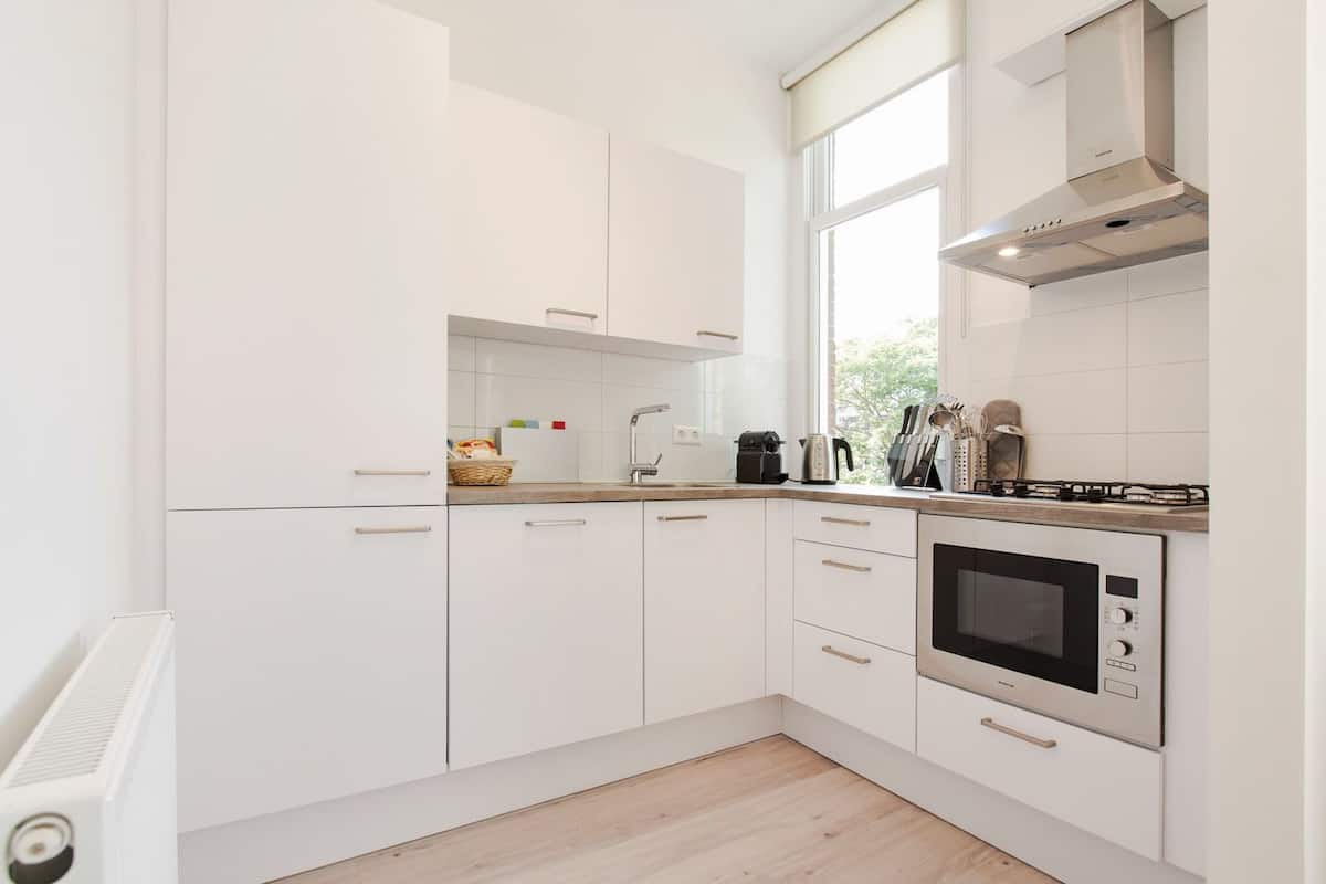 A modern kitchen with white cabinets, a built-in oven, a microwave, and a gas stove.